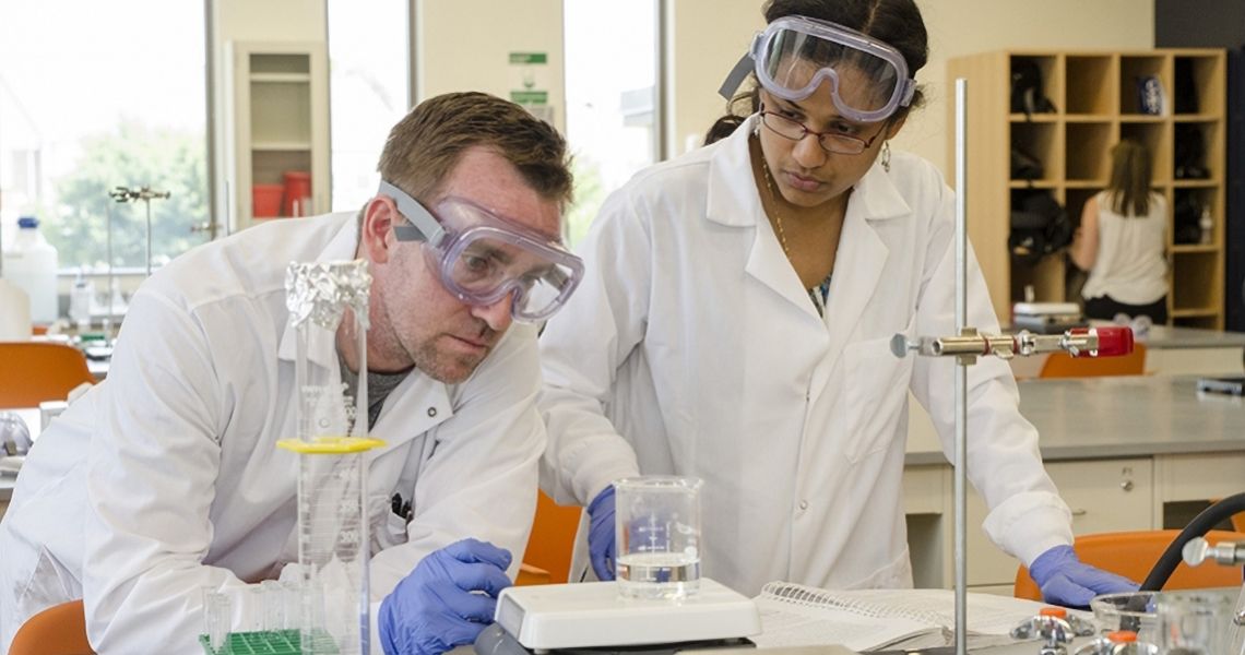 two people in lab gear working in a lab setting