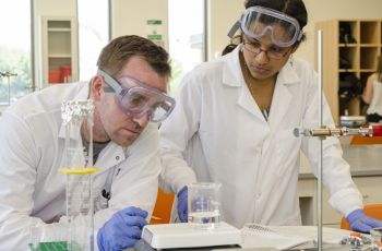 two people in lab gear working in a lab setting